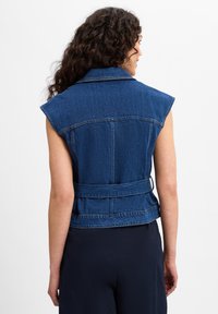 Jeans väst utan ärmar med en strukturerad krage, figursydd midja och bälte bak. I medelblå tvätt med en något blekt textur.