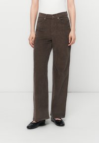 Bruine ribfluwelen broek met een recht model, voorzien van een hoge taille, zijvakken en subtiele verticale textuurdetails.