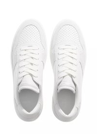 Hvite sneakers med perforerte detaljer, flate snøring og rund tå. Glatt materiale og minimalistisch design uten synlig merke.