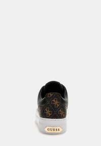Sneaker nera con un retro marrone a fantasia che presenta un design con logo. Suola bianca con un accento dorato metallico "GUESS". Texture liscia.