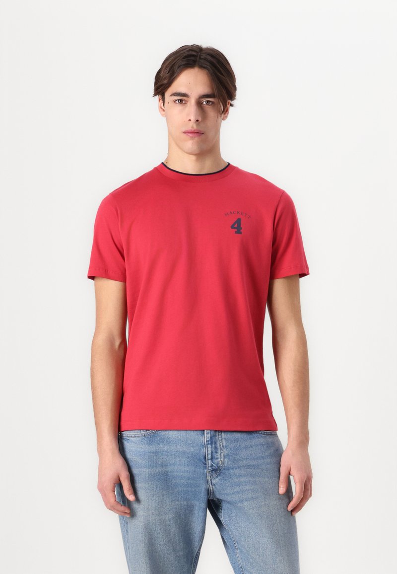 Rød bomull T-skjorte med korte ermer, rund hals og marineblå logo med tallet 4. Bært sammen med lyseblå jeans.