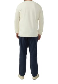 Lange mouwen crème katoenen shirt met een normale pasvorm, gecombineerd met donkerblauwe broek. Beide kledingstukken hebben een eenvoudige, onversierde stijl.