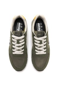 Baskets en tissu vert et maille avec des lacets blancs, des accents jaunes au talon, et un logo noir et blanc sur la languette. Design bicolore.