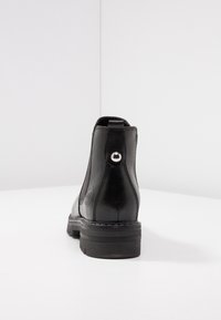 Zwarte leren enkelboot met ronde hak, elastische zijpanelen en een metallic accent aan de achterkant. Gladde textuur met gestikte details.