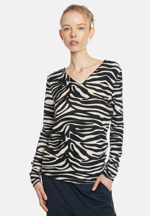 Black and cream long-sleeve top with a zebra stripe pattern, featuring a V-neckline and gathered detail at the waist. Soft, stretch fabric.