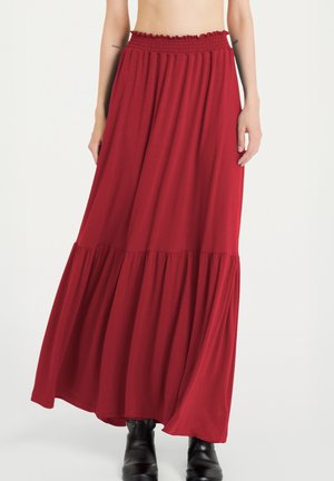 Gonna maxi rossa realizzata in tessuto morbido, con vita elasticizzata e design a strati, caratterizzata da una silhouette fluida e una lunghezza alla caviglia.