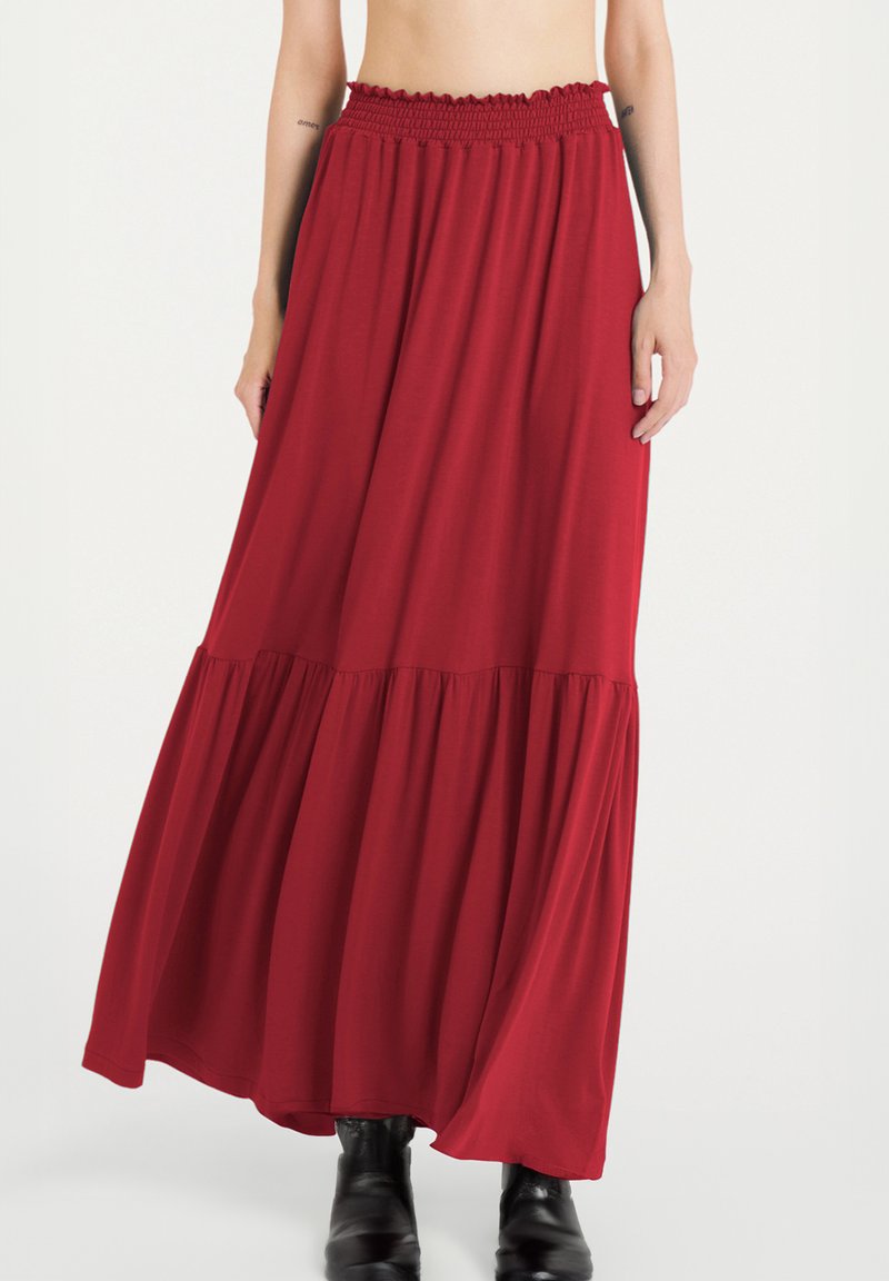 Gonna maxi rossa realizzata in tessuto morbido, con vita elasticizzata e design a strati, caratterizzata da una silhouette fluida e una lunghezza alla caviglia.