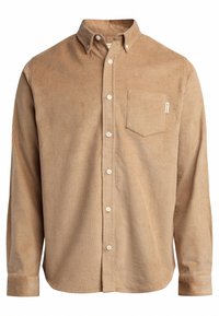 Chemise en velours côtelé marron avec col boutonné, manches longues, poche poitrine et boutons blancs. Le tissu présente une texture à rainures verticales.