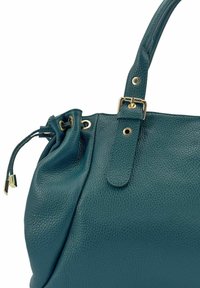 Sac à main en cuir bleu sarcelle avec une surface texturée, des accents en métal doré et une fermeture supérieure à cordon. Caractérisé par deux poignées et une forme structurée.