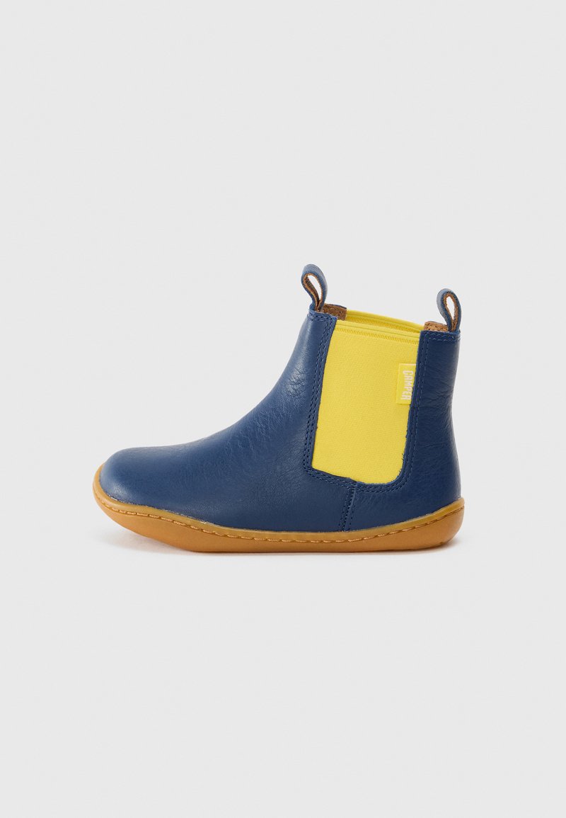 Botín de cuero azul hasta el tobillo con panel lateral elástico amarillo y suela marrón, que cuenta con dos tiradores en la parte superior para facilitar su colocación.