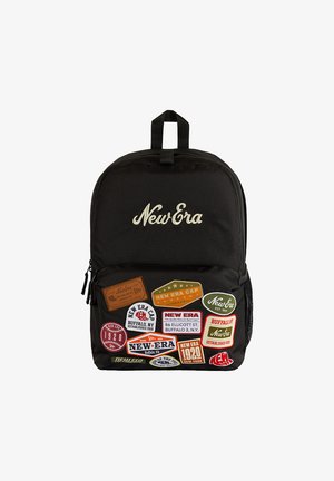 Sac à dos noir avec le logo "New Era" et plusieurs patchs colorés évoquant la marque New Era et des références à Buffalo, NY, sur la poche avant.