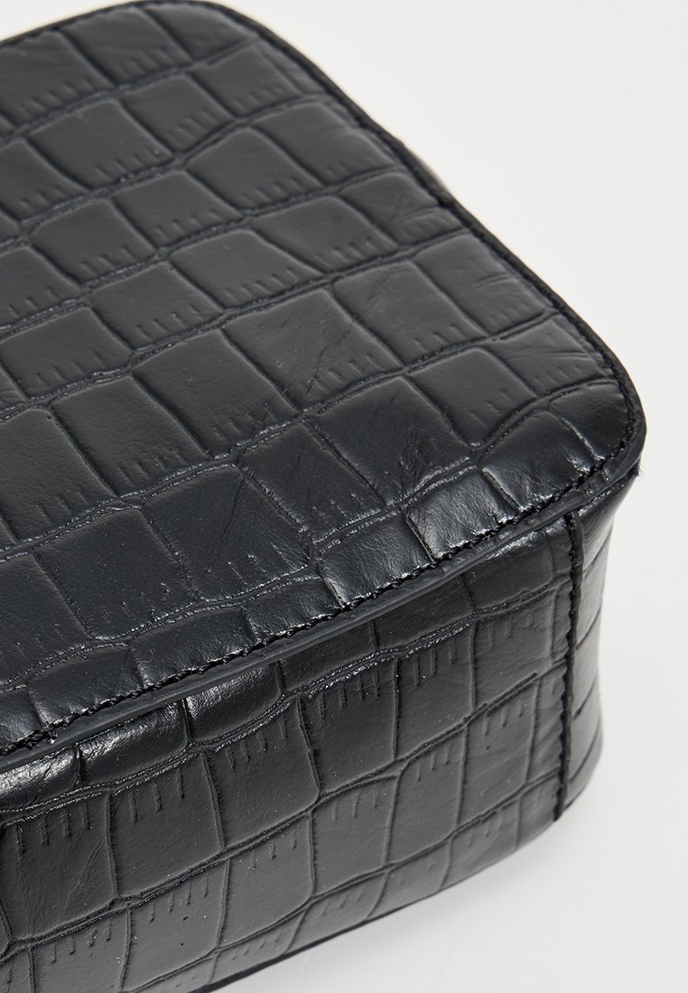 Schwarze Krokodilledertasche mit quadratischer Form, glatter Textur und verstärkten Nähten entlang der Kanten.
