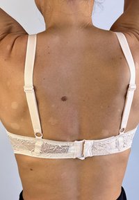 Sujeta de sujetador de encaje rosa claro con espalda de encaje, tirantes ajustables y cierre de gancho y ojo. Tejido suave con detalles de encaje floral a lo largo de la banda.