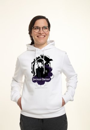 Hvid hættetrøje med sort og lilla grafisk design af en figur samt teksten "SOCIAL DISTANT." Blødt materiale, snøre i hætten, forlommer.