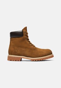 Hnedá semišová boot s hnedým koženým golierom, zlatými šnúrkami a gumovou podrážkou s robustným vzorom. Viditeľné logo Timberland.