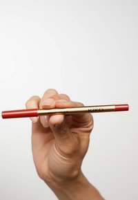 Röd läpppenna med ett guldmetallhölje märkt "CREAMY COLOUR" och "KIKO", som har en slät textur och en spetsig topp.