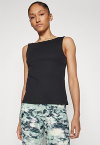 Top in maglia nera a coste con scollatura quadrata e design aderente, abbinato a leggings sportivi multicolori con motivo nuvoloso.