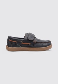 Zapato casual de cuero azul oscuro con correa de velcro, costuras marrones y suela de goma. Presenta cordones laterales y una suela texturizada.