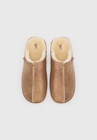 Pruunidest seemisnahast libisevad sussid, vooderdatud pehme koorevärvi karvase voodriga, pildistatud ülalt valgel taustal.