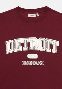 Vinr�öd sweatshirt med vit text "DETROIT" i en båge ovanför "EST. 1701" och "MICHIGAN" nedanför, rundad halsringning, varumärkesetikett ENDAST inuti kragen.