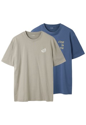 Twee T-shirts met korte mouwen en ronde hals, één beige met kleine citroenschijf grafiek, één blauw met gele tekst "c'est la vie" op de borst.