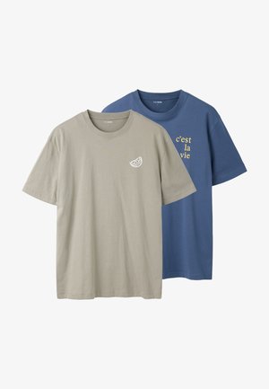 Twee T-shirts met korte mouwen en ronde hals, één beige met kleine citroenschijf grafiek, één blauw met gele tekst "c'est la vie" op de borst.
