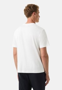 Hvid bomulds t-shirt med rund halsudskæring, korte ærmer og lige kant, vist fra ryggen. Blød tekstur, minimalistisk design.