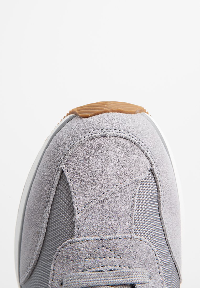 Sneaker gris avec une tige en suède doux et mesh, doté d'une semelle extérieure en caoutchouc texturé. Comprend des détails cousus et un bout rond.