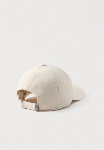 Μπεζ βαμβακερό καπέλο του μπέιζμπολ εμφανιζόμενο από πίσω με ρυθμιζόμενο υφασμάτινο λουράκι και μεταλλική αγκράφα σε λευκό φόντο.