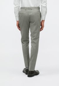 Ανοιχτό γκρι κομμένα παντελόνια με λεία υφή, διαθέτοντας δύο πίσω τσέπες και ευθεία γραμμή, συνδυασμένα με σκούρα καφέ παπούτσια.