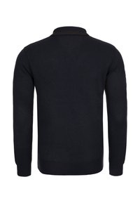 Musta neulepusero, jossa pitkät hihat ja poolokaulus. Varustettu resoreilla hihansuissa ja helmassa. Sileä pinta, ilman näkyviä kuvioita tai yksityiskohtia.