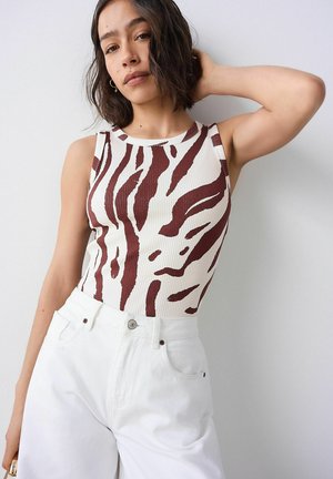 Wit geribbeld tanktop met bruine abstracte strepen, gecombineerd met hoog gekozen witte jeans. Eenvoudige ronde halslijn, mouwloos ontwerp.