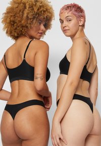 Black underwear set featuring a bralette and bikini-style bottoms. Soft fabric, minimal seams, thin straps, and a seamless design.