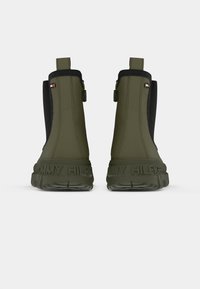 Žalios guminių ankle botų su juodomis elastingomis šoninėmis, logotipas išspaustas ant pado ir vilkimo juostele, kad būtų lengva apsiauti. Su tekstūruotu, patvariu dizainu.