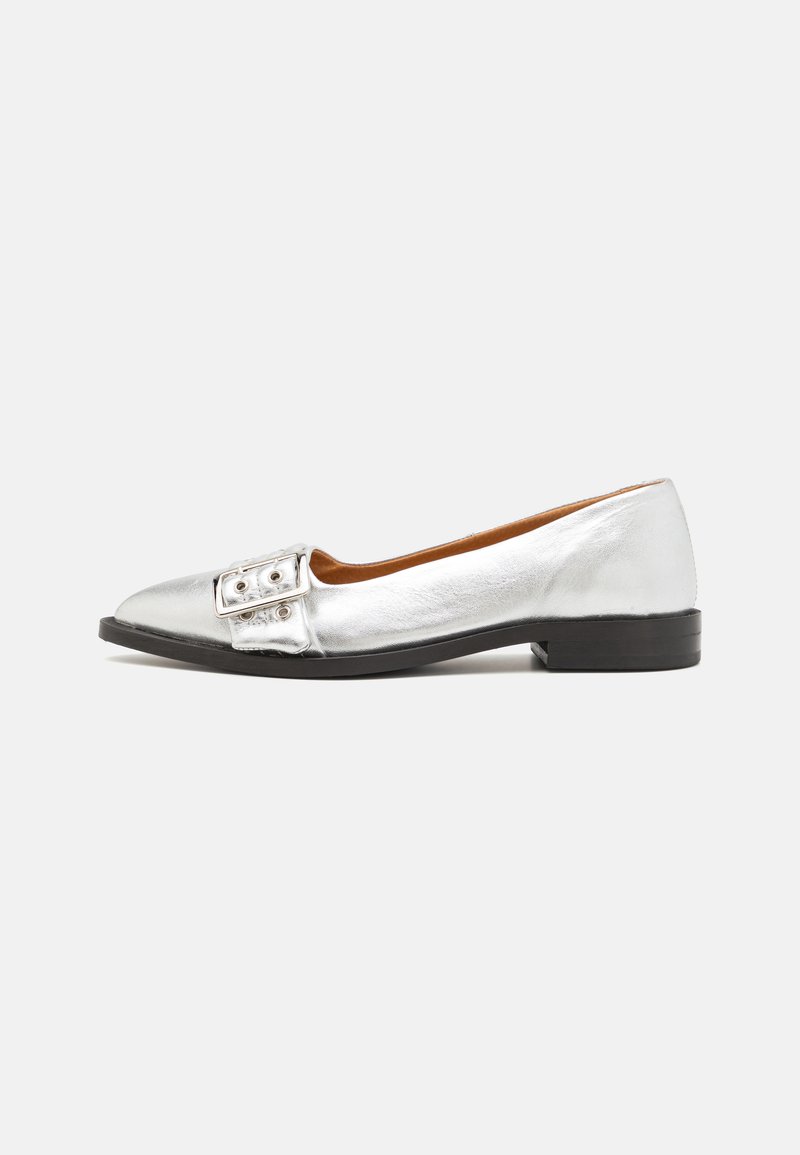 Silver flat shoe with a pointed toe, metallic leather finish, large decorative buckle on the front, and a black low heel.