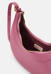 Różowa skórzana torebka na ramię o zaokrąglonym kształcie, złoty zamek błyskawiczny i brązowa podszewka wnętrza. Posiada metkę marki w środku.