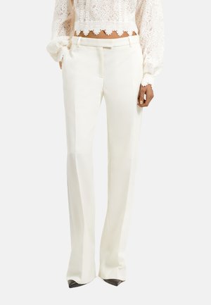 Pantalons blancs ajustés avec une texture lisse, une coupe droite et des lignes épurées. Dotés de poches latérales et d'une fermeture frontale dissimulée.