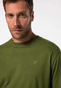 T-shirt a girocollo verde oliva realizzato in morbido cotone. Presenta un sottile logo "JP 1880" in una tonalità più chiara sul petto. Texture liscia.