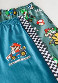 Lasten shortsit, joissa on kaksi kuosia: yksi tasainen teal-väri Mario Kart -grafiikalla ja toinen kuvioitu hahmoilla ja ruutukuvioin.