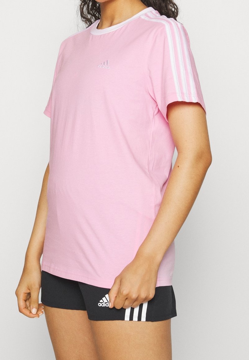 Rosa t-shirt med kort ärm och vit krage samt tre vita ränder på axlarna. Har en liten vit adidas-logotyp på bröstet.