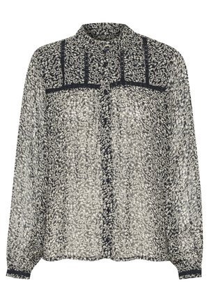 Genomskinlig blus med långa ärmar i svart och vitt blommönster, med knappar, mandarin-krage och strukturerade detaljer längs bröstet.