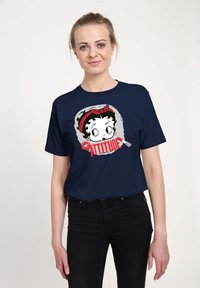 T-shirt in cotone blu navy con una grafica di un personaggio con una fascia a pois rossi e la parola "ATTITUDE" in caratteri rossi bold.