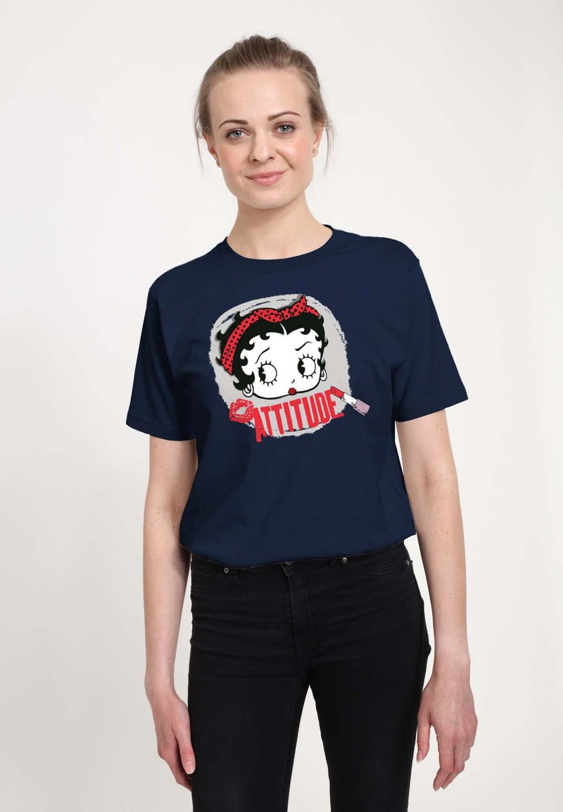 T-shirt in cotone blu navy con una grafica di un personaggio con una fascia a pois rossi e la parola "ATTITUDE" in caratteri rossi bold.