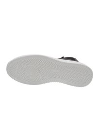 Zapatilla negra con una suela de goma blanca, que presenta un patrón de relieve en la suela. La parte superior tiene un acabado liso con un diseño de corte bajo.