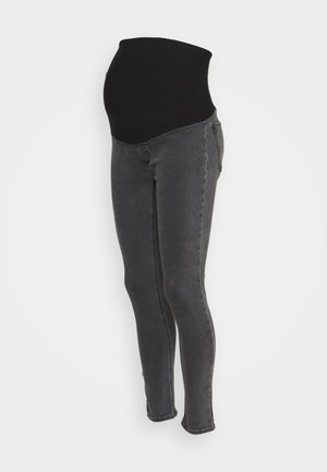 Jean de maternité gris foncé avec un panneau en tissu stretch noir conçu pour soutenir le ventre d’une femme enceinte.