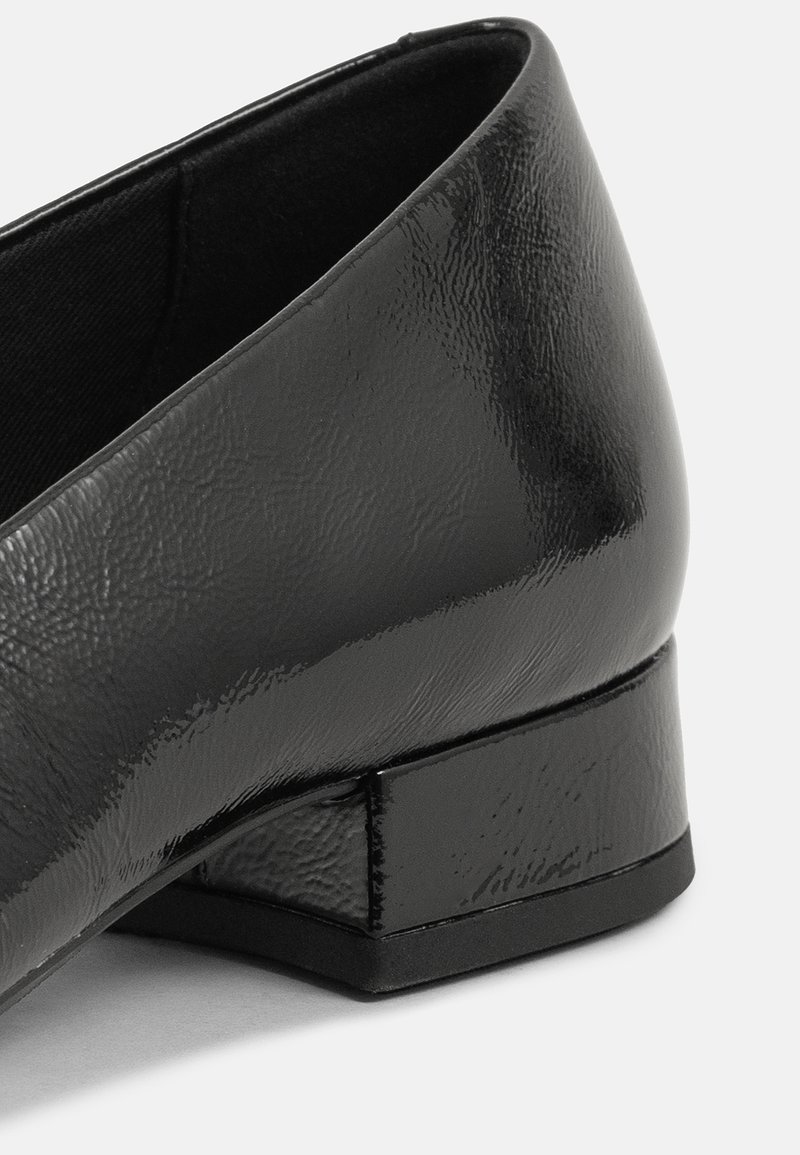 Chaussure plate en cuir noir avec une finition texturée, un petit talon carré, et une doublure intérieure lisse. Présente un design épuré sans embellissements.