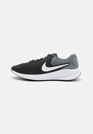 Zapatilla deportiva en negro y gris con parte superior de malla, entresuela blanca y suela exterior texturizada en negro. Presenta un acento del logo en blanco en el lateral.