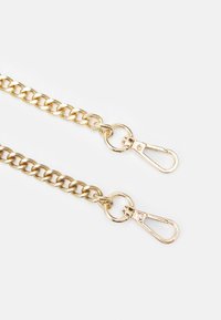 Catena in metallo dorato con grandi maglie, dotata di due attacchi a morsetto ad ogni estremità. La superficie è liscia e lucida, riflettendo la luce.