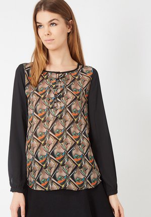 Blusa negra de manga larga con delante estampado que presenta formas geométricas en marrón, naranja y verde. El delantero tiene un detalle de botones en el escote.