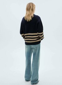 Maglione lavorato a maglia navy con strisce panna, vestibilità comoda e polsini a coste, abbinato a jeans in denim blu chiaro a gamba larga.